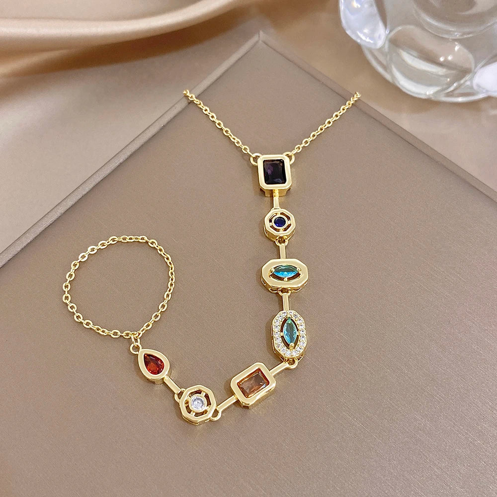 Gold-tone geometric zircon bracelet with square links, blue oval accents, and dangling charm