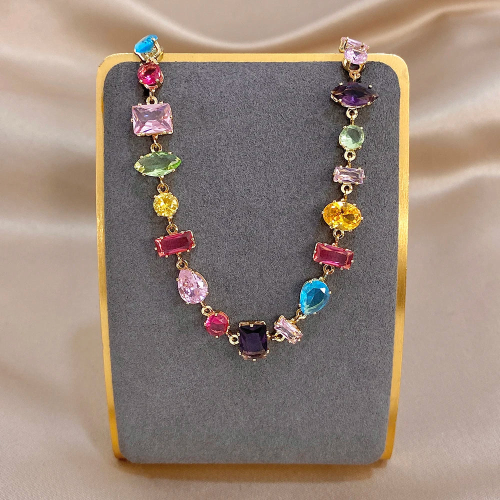 Colorful geometric zirconia link bracelet on display card, gold-tone chain and stones.