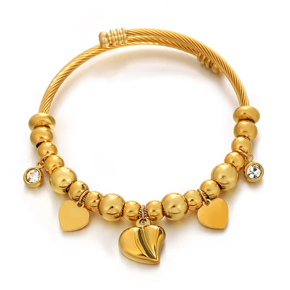 Gold-tone beaded bracelet with small crystal dangles and heart charm accents