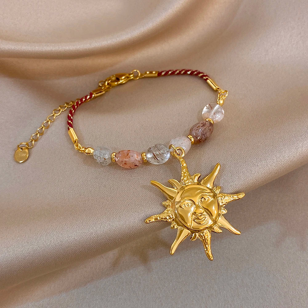 Gold-tone beaded rope chain bracelet with mixed clear, peach, and red cord sun charm