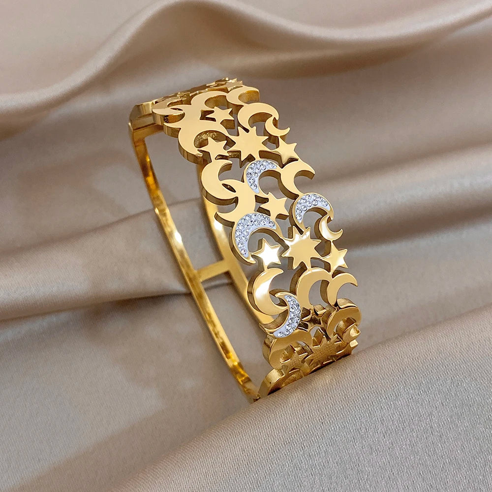Gold-tone open cuff bangle with star and crescent cutouts and sparkling crystal details