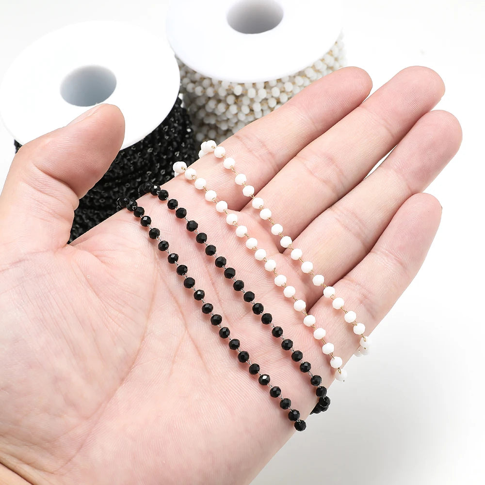 Beaded necklace chains draped over hand: black and white pearl-like beads