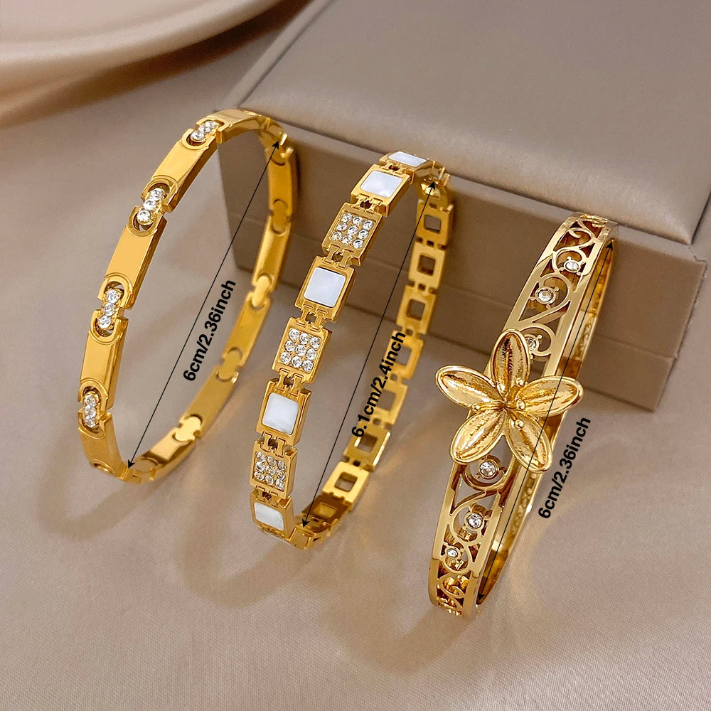 Gold-plated cuff bangles with hollow flower centerpiece and square crystal link accents, set