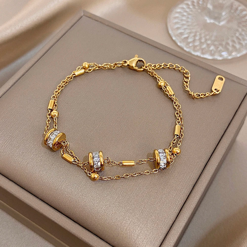 Gold double-layer chain bracelet with rhinestone bead stations and toggle clasp.