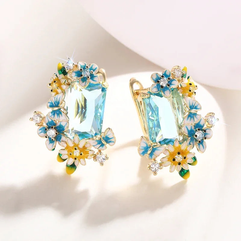 Gold-tone floral drop earrings showing front face with aqua crystal and flower charm detail