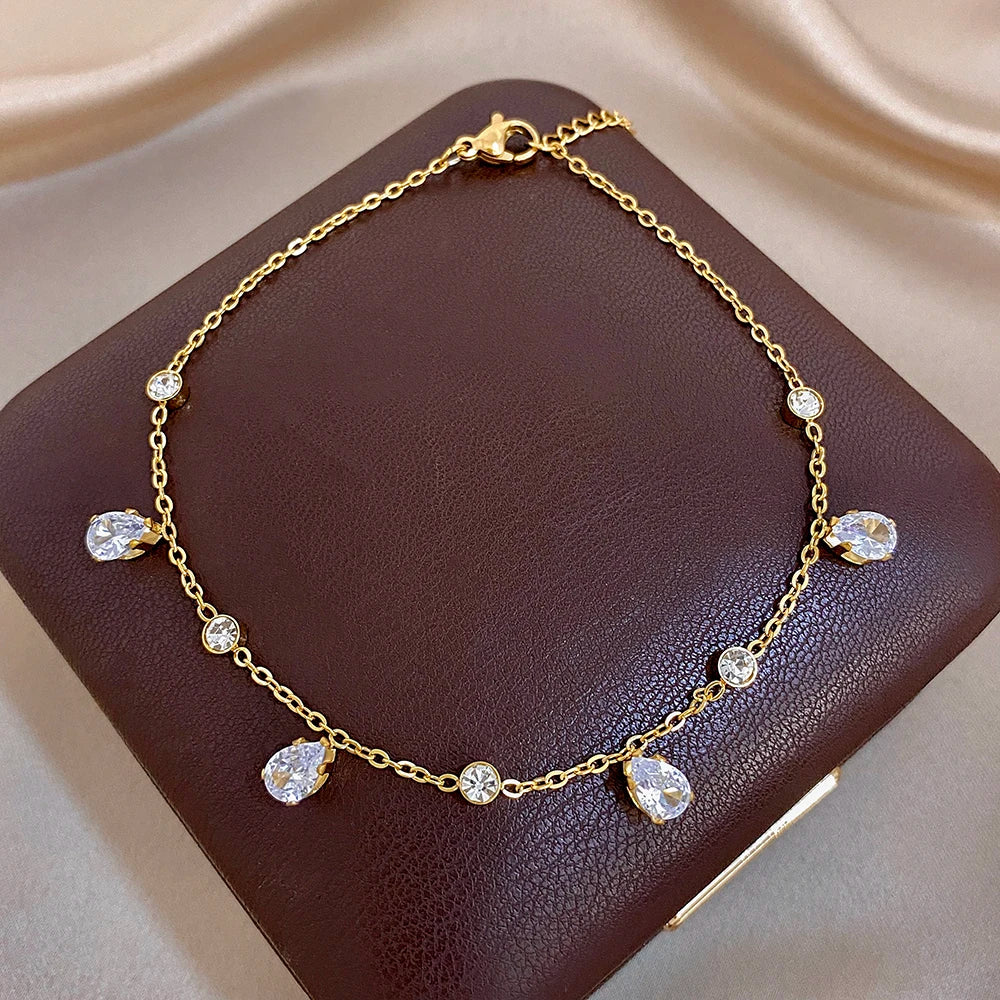 Gold-tone teardrop zircon link bracelet on dark card with round and teardrop stones