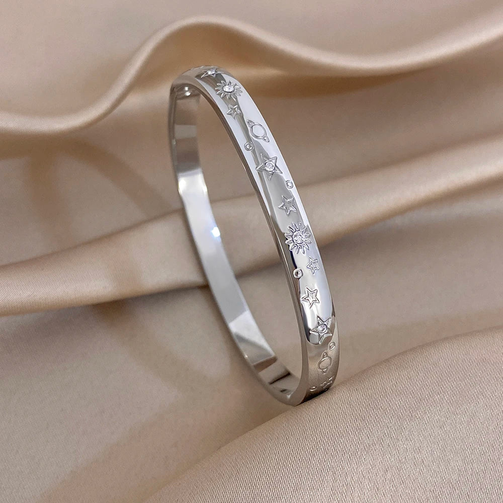 Silver-tone wide cuff bangle with engraved stars and crystal-like stones, close-up