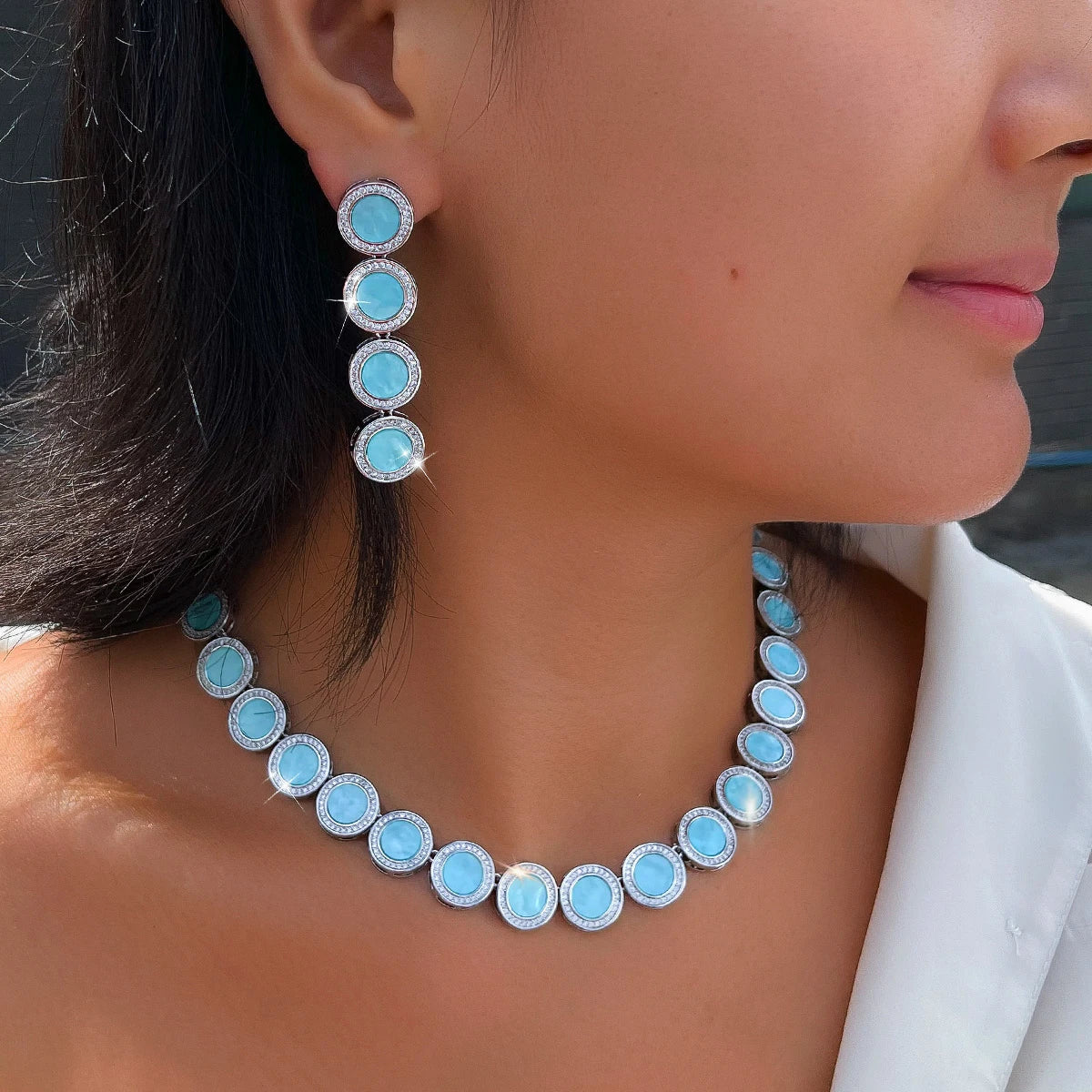 Light blue round halo necklace and long drop earrings worn together