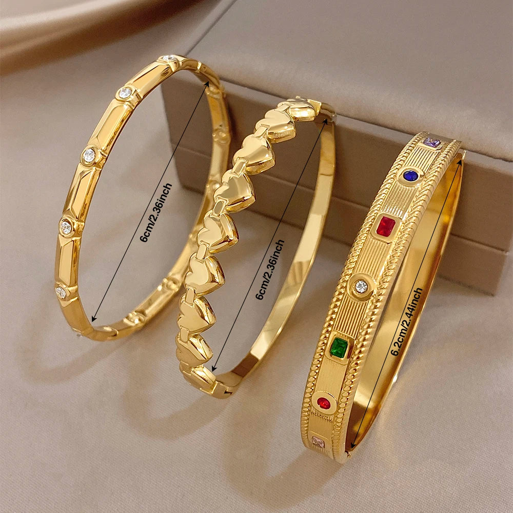 Set of gold-tone bangles: heart-link, bar, and colorful gemstone inset cuffs