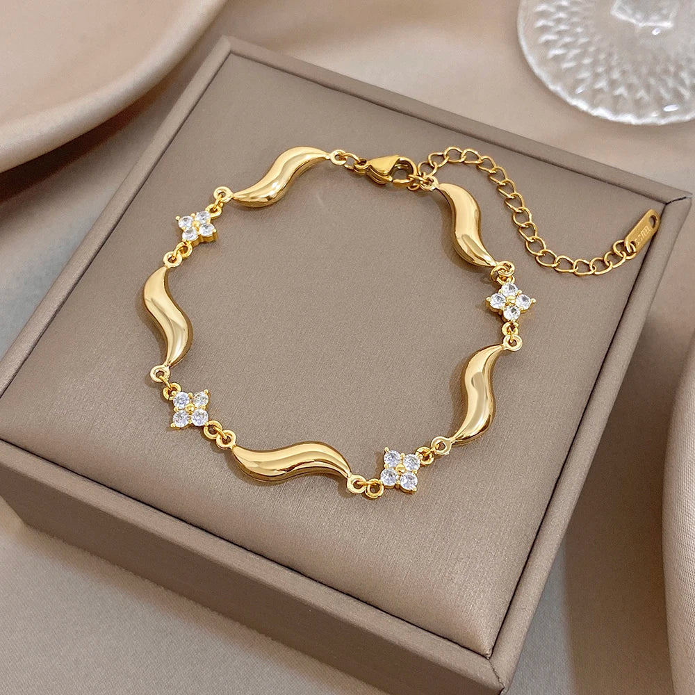 Gold-plated circular wave bracelet with crystal flower stones, shown in gift box