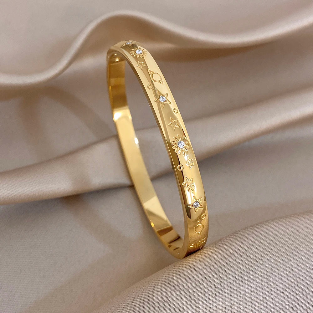 Gold-tone engraved star cuff bangle with crystal-like stones, close-up