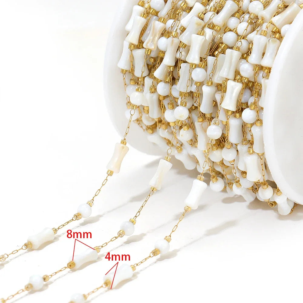 Close-up of white shell-style bead chain strand with gold links and size reference markings