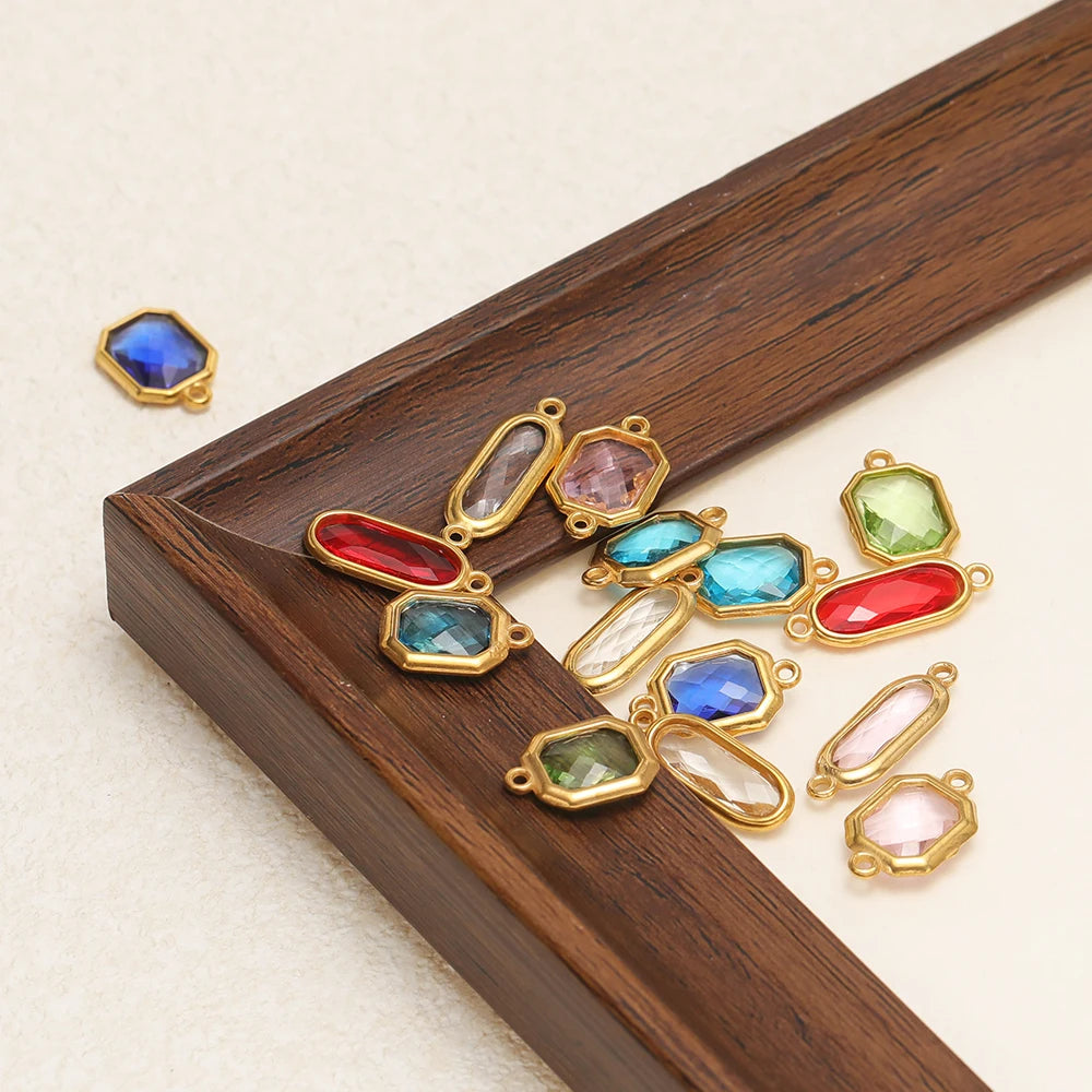 Assorted faceted glass charm connectors in blue, green, red, and pink with gold-tone loops