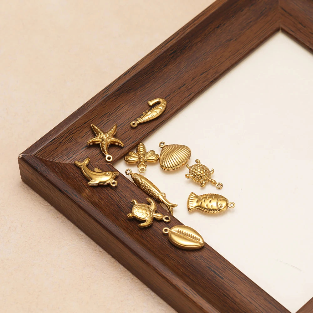 Gold-toned ocean animal hollow charms, dolphin, starfish, turtle, fish on wooden tray