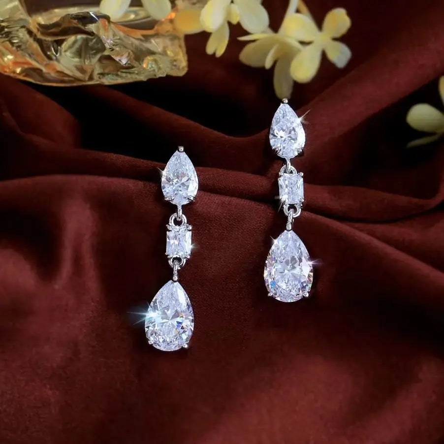 Pair of silver-tone dangle earrings with pear-cut crystals and rectangular center stones.
