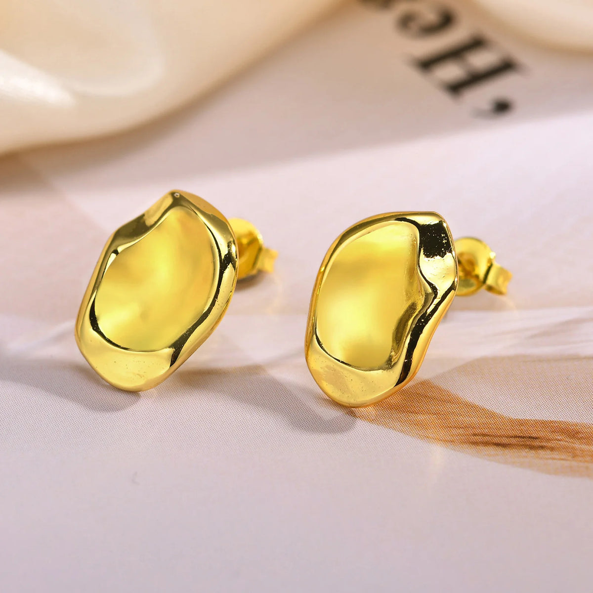Geometric gold-tone stud earrings with curved polished fronts and butterfly posts