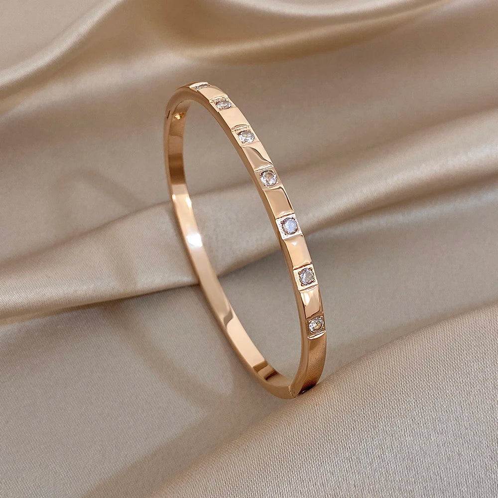 Rose gold cuff bangle with slim stone bezel strip and small clear square stones