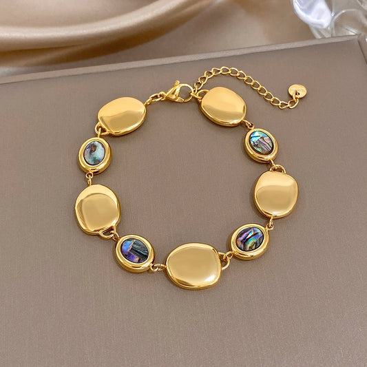 Gold-tone link bracelet with glossy oval discs and iridescent abalone shell inlays