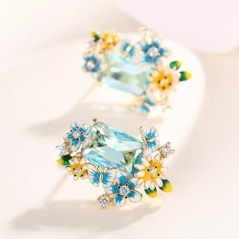 Gold-tone floral drop earrings close-up view of aqua crystal and flower cluster design