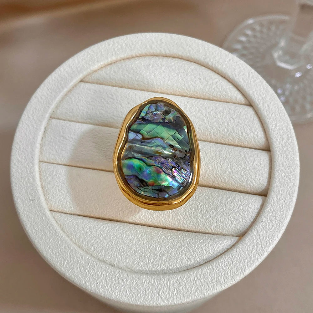 Gold-plated abalone shell ring on white cushion, iridescent teardrop-oval stone