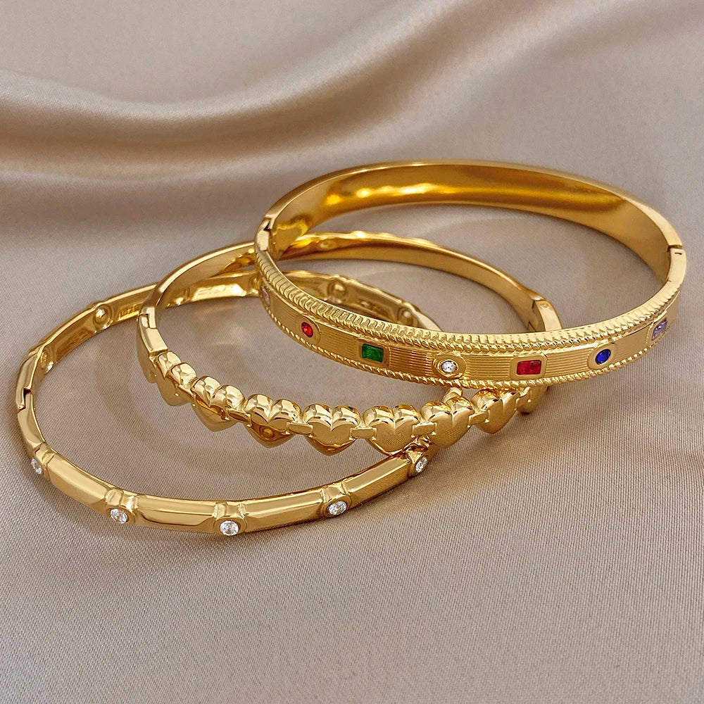 Gold-tone cuff bangles with heart links and multicolor gemstone detail